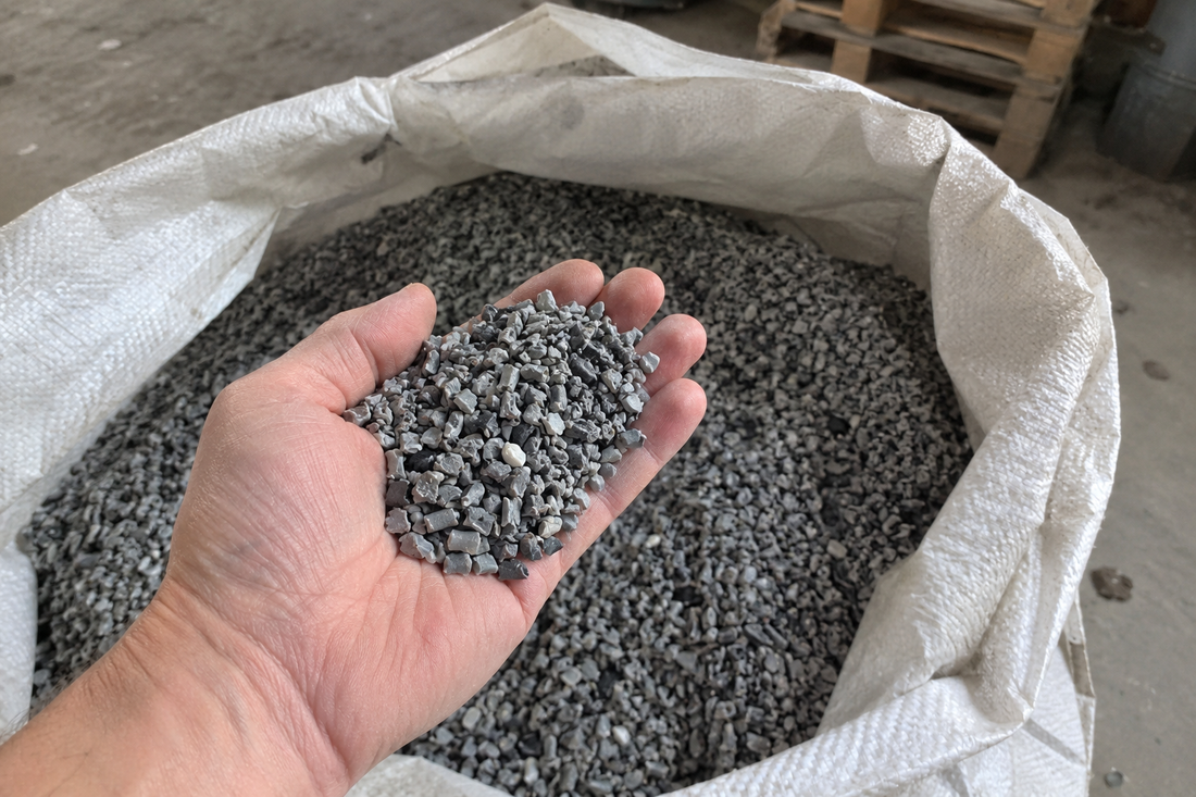 Hand mit grauem Kunststoffgranulat über einem Sack voller Granulat (KI-generiertes Bild)